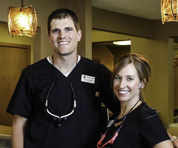 Drs. Jennifer and Eric Veurink standing in dental office and smiling.